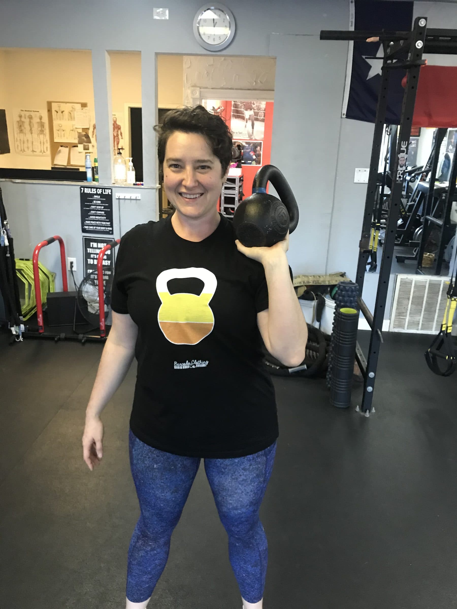 Client pressing a kettlebell in front of the Texas flag at PowerHouseATX